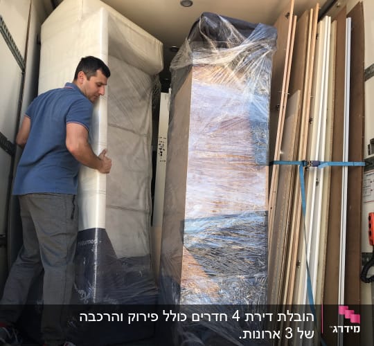 אדם מעביר רהיטים עטופים במשאית הובלה